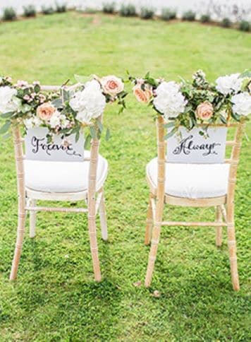 Two chairs at a wedding standing on a grass